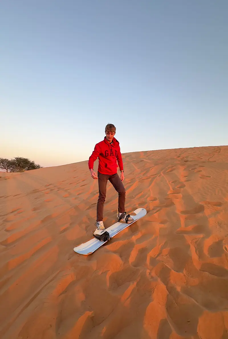 a man enjoying sandboarding experience in ras al khaimah desert